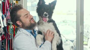 alegre barbudo veterinário acariciando adorável cachorro às dele clínica video