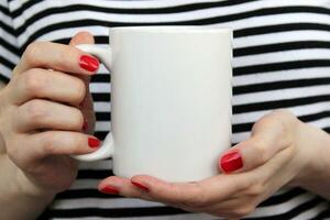 White ceramic mug in woman's hands, product mockup photo