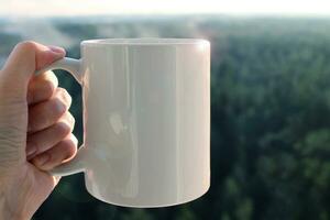 Travel ceramic white mug in hand, mockup photo