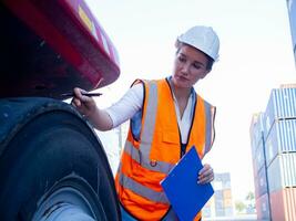 female woman lady person human people white hardhat helmet safety check up tire forklift crane cargo warehouse logistic import export copy space manufacturing manager supervisor employ photo