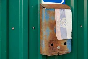 old rusty russian mailbox on the wall with extremely faded small fabric russian flag with with coat of arms photo