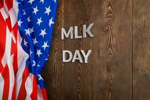 the word MLK day laid with silver metal letters on wooden surface with crumpled USA flag at left side photo