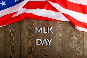 the word MLK day laid with silver metal letters on wooden surface with crumpled USA flag at upper side photo