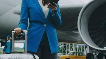 businesswoman hand holding tablet while carrying luggage with airport background video