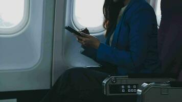 in viaggio e tecnologia. volante a primo classe. bella giovane imprenditori donna utilizzando smartphone mentre seduta nel aereo. video