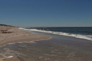 yo amado el Mira de esta playa escena como el olas estrellado en. el bonito Mira de el de capa blanca navegar corriendo en a el costa. el arena demostración un diferente tono a dónde el agua una vez era. foto