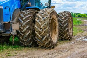 dirty double wheels of agriculture tractor at summer day photo