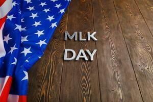 the word MLK day laid with silver metal letters on wooden surface with crumpled USA flag at left side photo