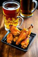 Grilled chicken wings with a glass of beer on a wooden table. AI Generative photo