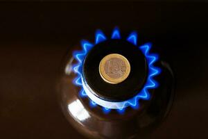 gas stove burner with one euro coin laid on top, burning natural gas with blue flame photo