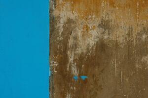 old concrete with brown plaster wall partially painted in blue, texture and background photo
