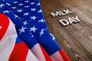 the word MLK day laid with silver metal letters on wooden surface with crumpled USA flag at left side photo