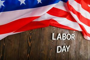 words labor day laid with silver metal letters on wooden surface with crumpled USA flag on left side photo