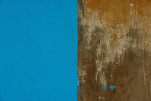 old concrete with brown plaster wall partially painted in blue, texture and background photo