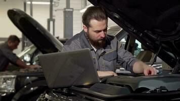 auto onderhoud arbeider gebruik makend van laptop, onderzoeken motor van een auto video