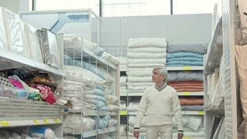Elderly man walking in home department store, shopping for bedding video