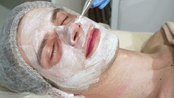 Relaxed happy handsome man enjoying facial masks at spa center video