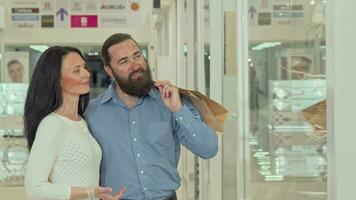 Happy mature couple looking at clothing store showcase at the shopping mall video