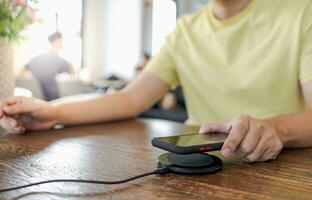 cargando móvil teléfono batería con inalámbrico cargando dispositivo en el mesa. teléfono inteligente cargando en un cargando almohadilla. móvil teléfono cerca inalámbrico cargador moderno estilo de vida concepto. foto