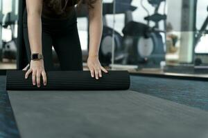 Fitness woman folding exercise mat before working out in yoga studio. rolling Yoga mat  after training healthy lifestyle photo