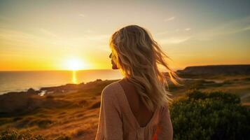 a young woman standing outdoors looking at the sunset photo