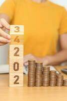 flipping 2023 to 2024 year block with Coins stack. Money, Budget, tax, investment, financial, savings and New Year Resolution concepts photo