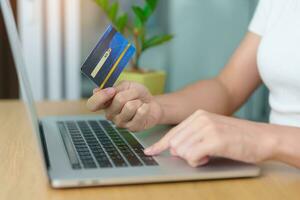 woman hand holding credit card and using laptop for online shopping while making order at home. Marketplace platform website, technology, ecommerce, digital banking and online payment concept photo