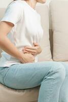 Woman having abdomen pain on the sofa at home. Liver cancer and Tumor, kidney cancer, Jaundice, Viral Hepatitis, Cirrhosis, Failure, Enlarged, Hepatic Encephalopathy, Stomach and health concept photo