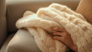 cozy wool blanket on sofa hand holding pillow for relaxation photo