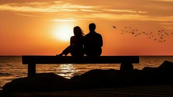 silhouette couple sitting on jetty at sunset photo