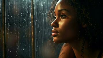 young african woman looking out of a rain soaked window photo