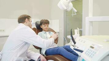 masculino dentista educando pequeño chico acerca de dental higiene video