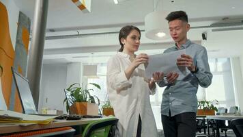 Two young business entrepreneurs going through papers at the office video