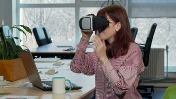 maduro mujer de negocios disfrutando utilizando virtual realidad auriculares a su lugar de trabajo video