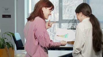 Rear view shot of two female colleagues discussing business graphics video