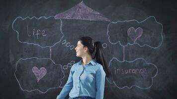 le femme qui écrit la vie Assurance sur le tableau noir est content et pacifique. video