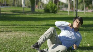 Young man with loss of balance, sitting in the park. video