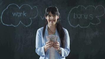 Woman writing Salary on blackboard looks with happy and profitable expression. video