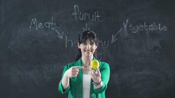 Woman writing Healthy Foods on blackboard looks at camera happy and full of life. video