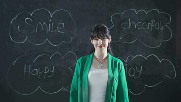 Woman writing smile on blackboard smiles at camera. video