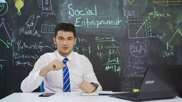 Businessman writes on blackboard Social entrepreneur and speaks to camera. video