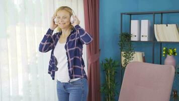 mujer mirando fuera el ventana y escuchando a música con auriculares. video