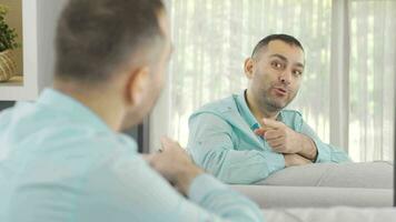 homme avec mental et psychologique problèmes des rires dans de face de le miroir. video