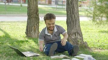 college dwerg leerling aan het doen huiswerk in de park proberen naar concentreren Aan lessen. video