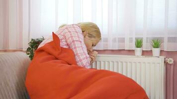 The woman leaning on the heater is cold. video