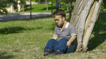 Dwarf young man sitting on the ground outdoors with fear. video