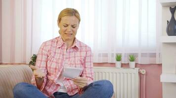 Woman leaning on heater looking at high bill. video