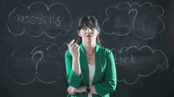 The woman writing a question on the blackboard looks at the camera and solves the question. video