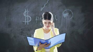 Woman writing Financial Crisis on blackboard looks at camera worriedly. video