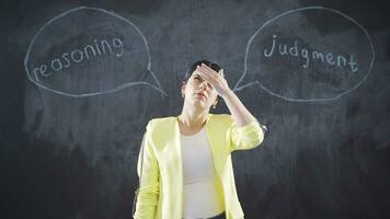 The woman writing Reasoning on the blackboard looks at the camera with a smile. video